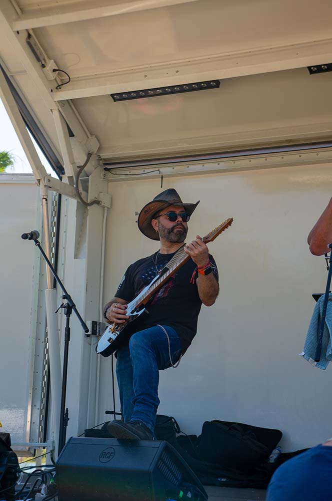 man playing guitar on stage with cowboy hat